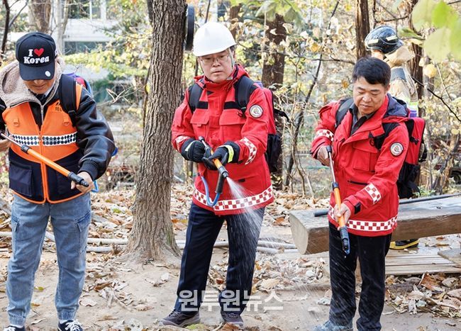 진교훈 서울 강서구청장(가운데)이 21일 오후 우장산 일대에서 열린 ‘유관기관 합동 산불진압훈련’에서 등짐펌프를 매고 산불진화대원과 함께 잔불진화작업을 하고 있다.